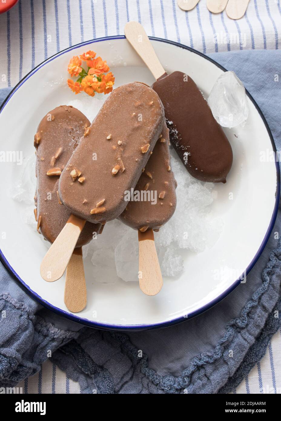 Quattro gelati al cioccolato su un piatto pieno di cubetti di ghiaccio. Tre su un palo e quello nero isolato. Foto Stock