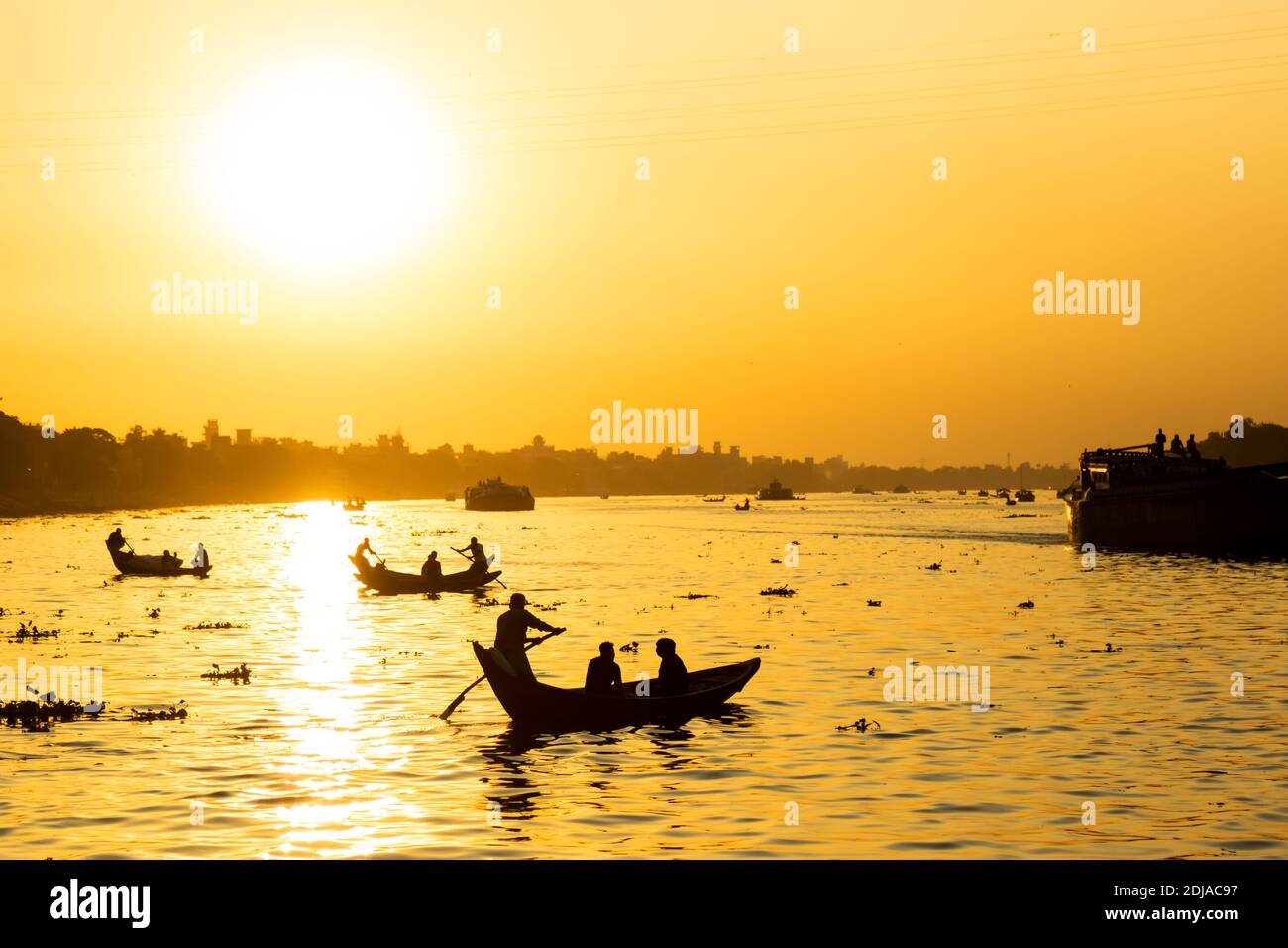 Vista magica e panoramica sul fiume Buriganga al tramonto. Centinaia di barche attraversano il fiume principale di Dhaka creando una panoramica silhouette retroilluminato Foto Stock
