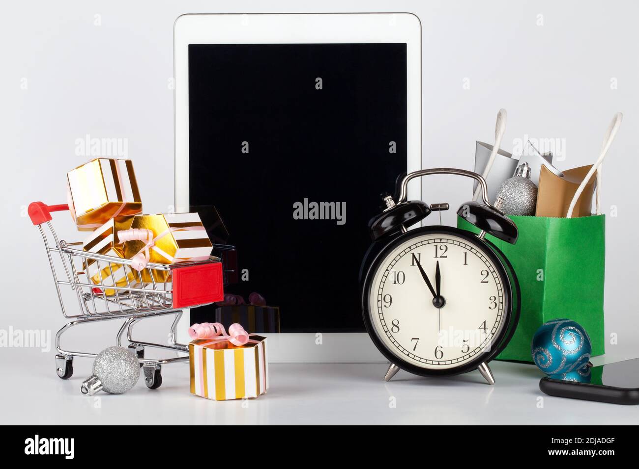 Online, shopping natalizio. Carrello per supermercati con scatole regalo, tablet pc, telefono cellulare e orologio su sfondo bianco. Spazio per fotocopie Foto Stock