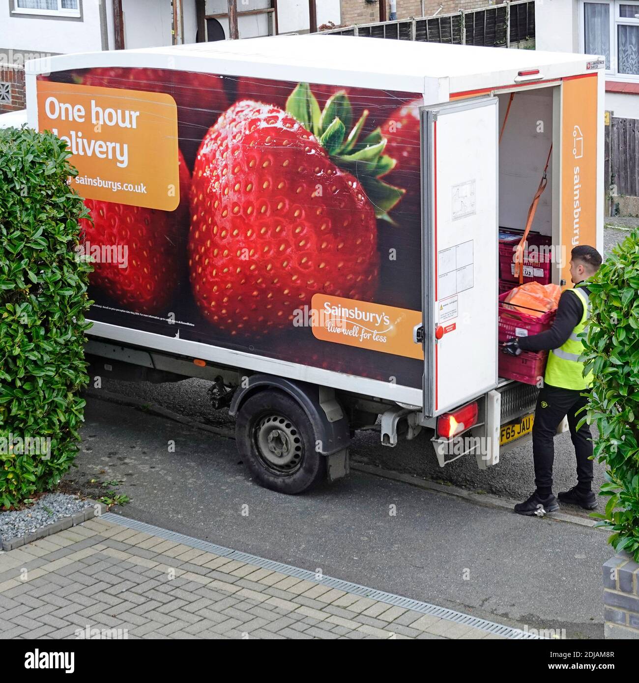 Guardando verso il basso Sainsburys supermercato online food shopping consegna driver e lato di furgone pubblicità fragola & consegna di un'ora Essex Inghilterra Regno Unito Foto Stock