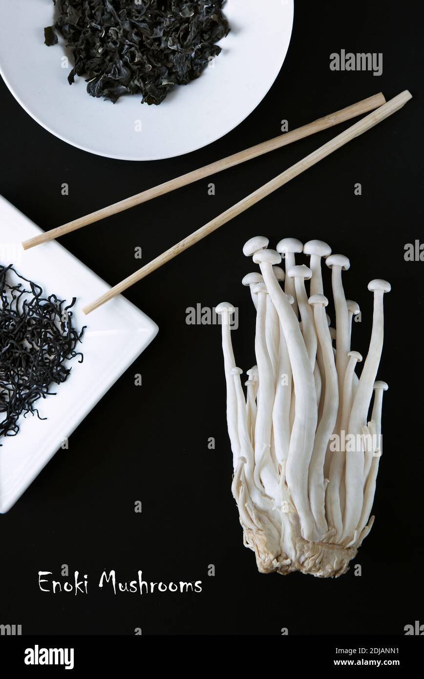 Composizione artistica dei prodotti alimentari asiatici - funghi Enoki e alghe secche su sfondo nero. Pranzo vegetariano. Cibo sano. Promozione Concept Foto Stock
