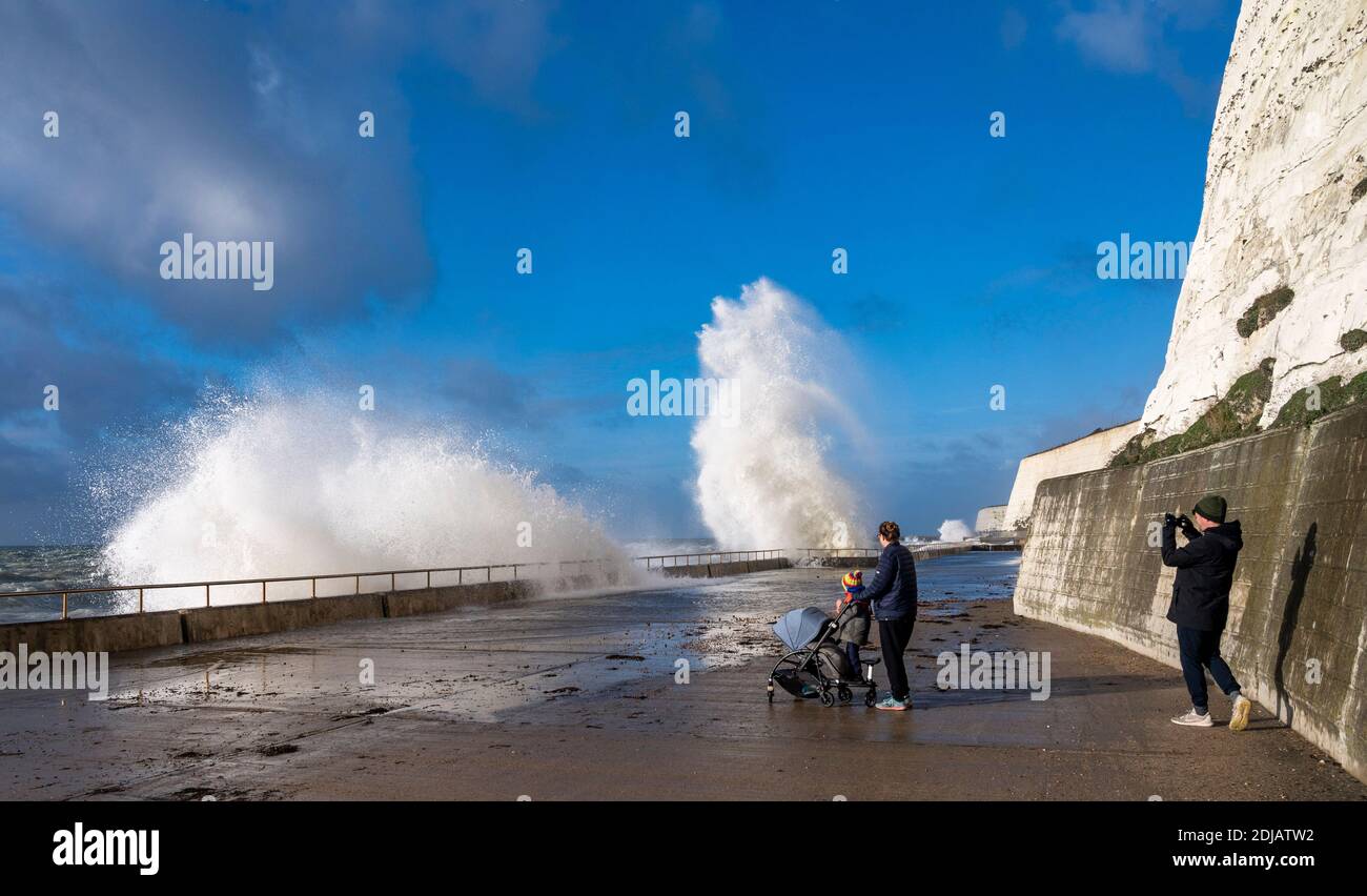 Brighton UK 14 dicembre 2020 - i camminatori guardano le onde che si infrangono in una giornata ventosa lungo la passeggiata sotto la scogliera di Saltdean sul lungomare vicino a Brighton ad alta marea . Le previsioni del tempo sono per i venti e le docce più forti da spargere attraverso le parti della Gran Bretagna ma con le temperature che sono più calde che nei giorni recenti: Credit Simon Dack / Alamy Live News Foto Stock