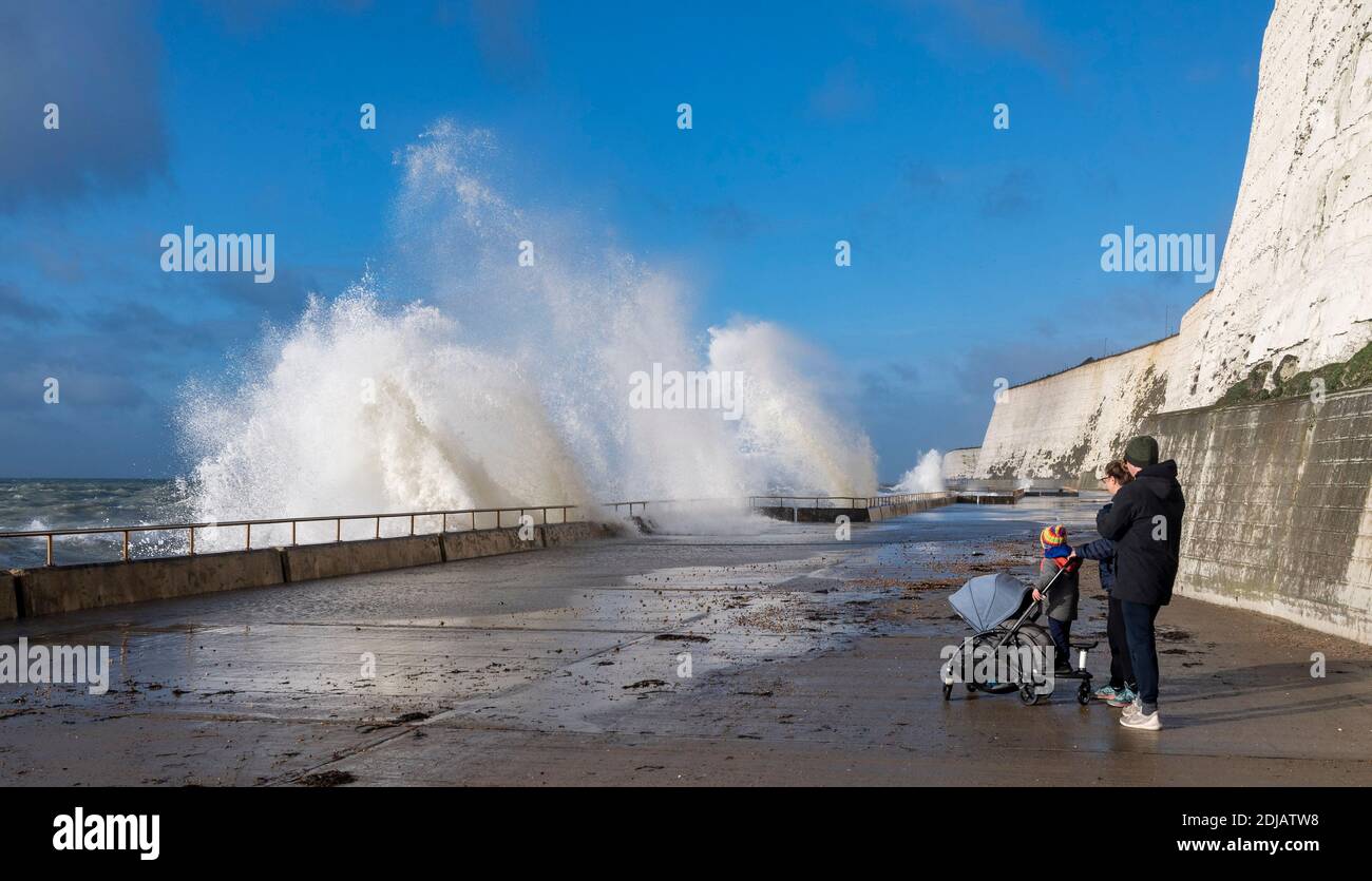 Brighton UK 14 dicembre 2020 - i camminatori guardano le onde che si infrangono in una giornata ventosa lungo la passeggiata sotto la scogliera di Saltdean sul lungomare vicino a Brighton ad alta marea . Le previsioni del tempo sono per i venti e le docce più forti da spargere attraverso le parti della Gran Bretagna ma con le temperature che sono più calde che nei giorni recenti: Credit Simon Dack / Alamy Live News Foto Stock