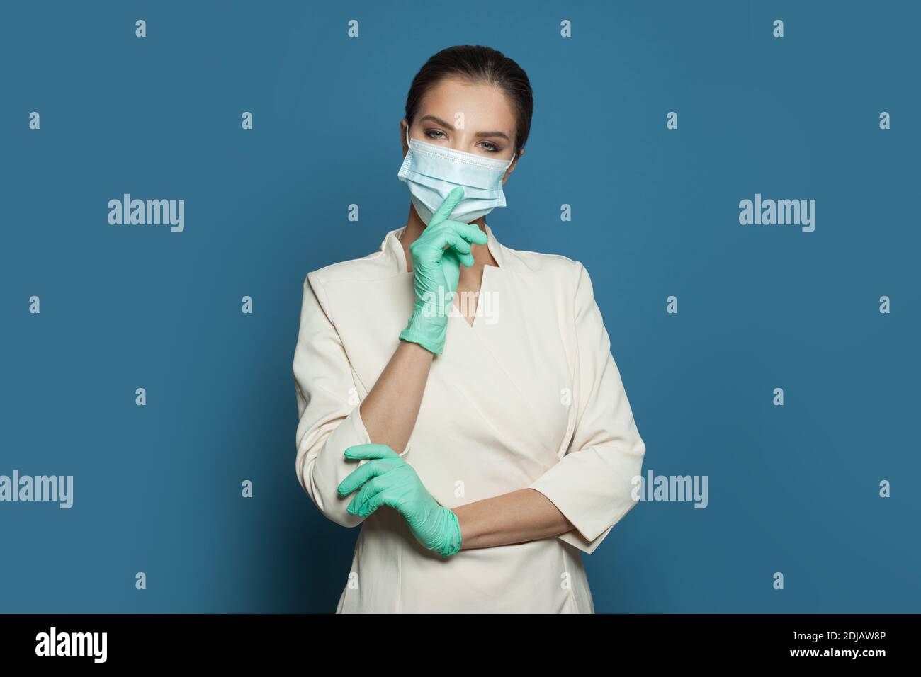 Medico chirurgo in maschera medica protettiva e guanti chirurgici su sfondo blu Foto Stock