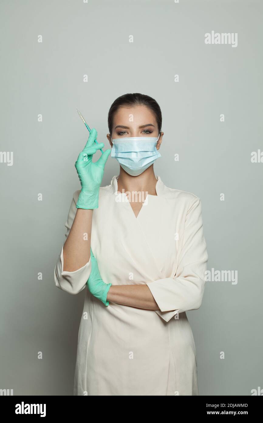 Donna medica ottimista con siringa su bianco. Medicina, cosmetologia e concetto di vaccinazione Foto Stock
