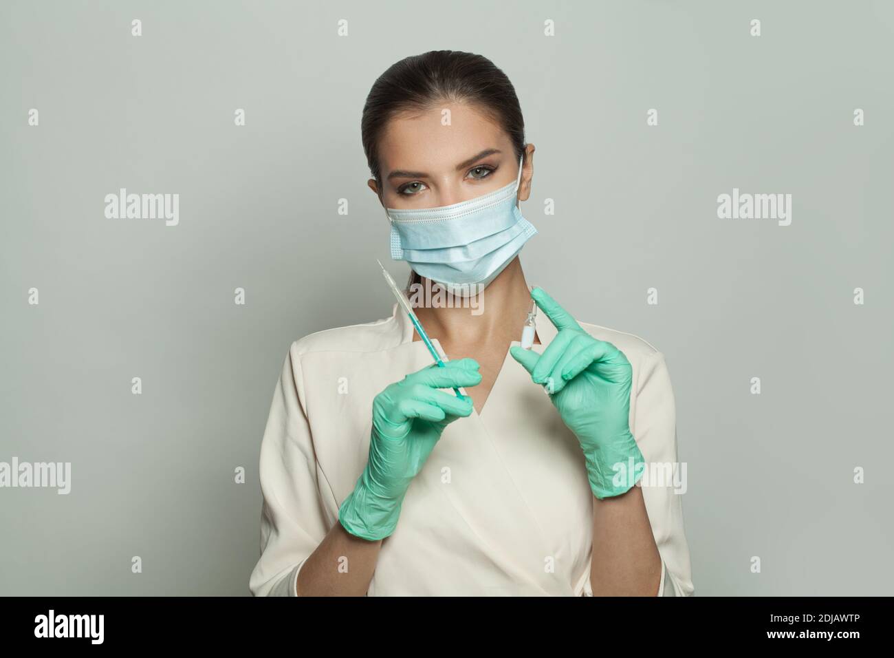 Donna medica ottimista che tiene la fiala per iniezione e la siringa su bianco. Medicina, cosmetologia e concetto di vaccinazione Foto Stock