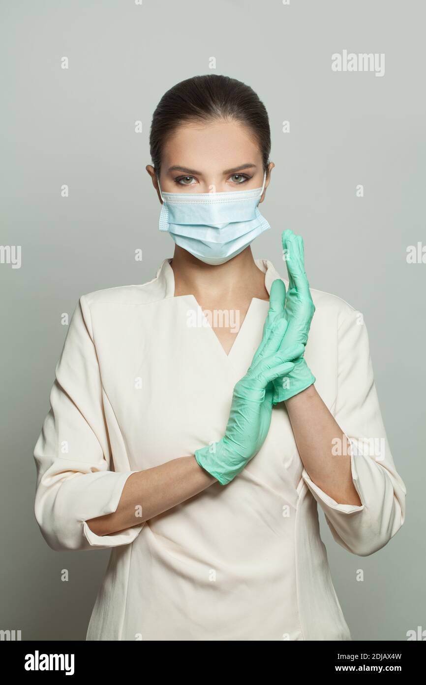 Medico chirurgo donna in maschera medica protettiva e guanti chirurgici su sfondo bianco Foto Stock