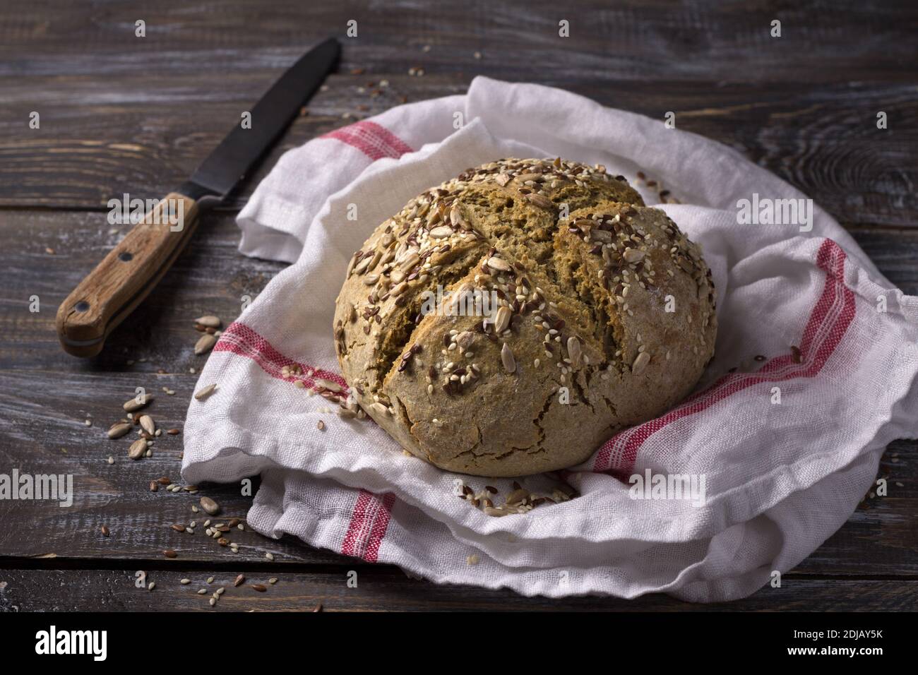 Semplice pane rustico di avena di segale senza lievito con semi su un tavolo di legno, fuoco selettivo Foto Stock