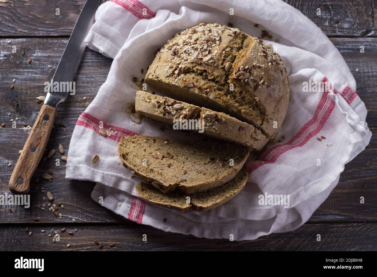 Semplice pane rustico di avena di segale senza lievito con semi su un tavolo di legno, fuoco selettivo Foto Stock