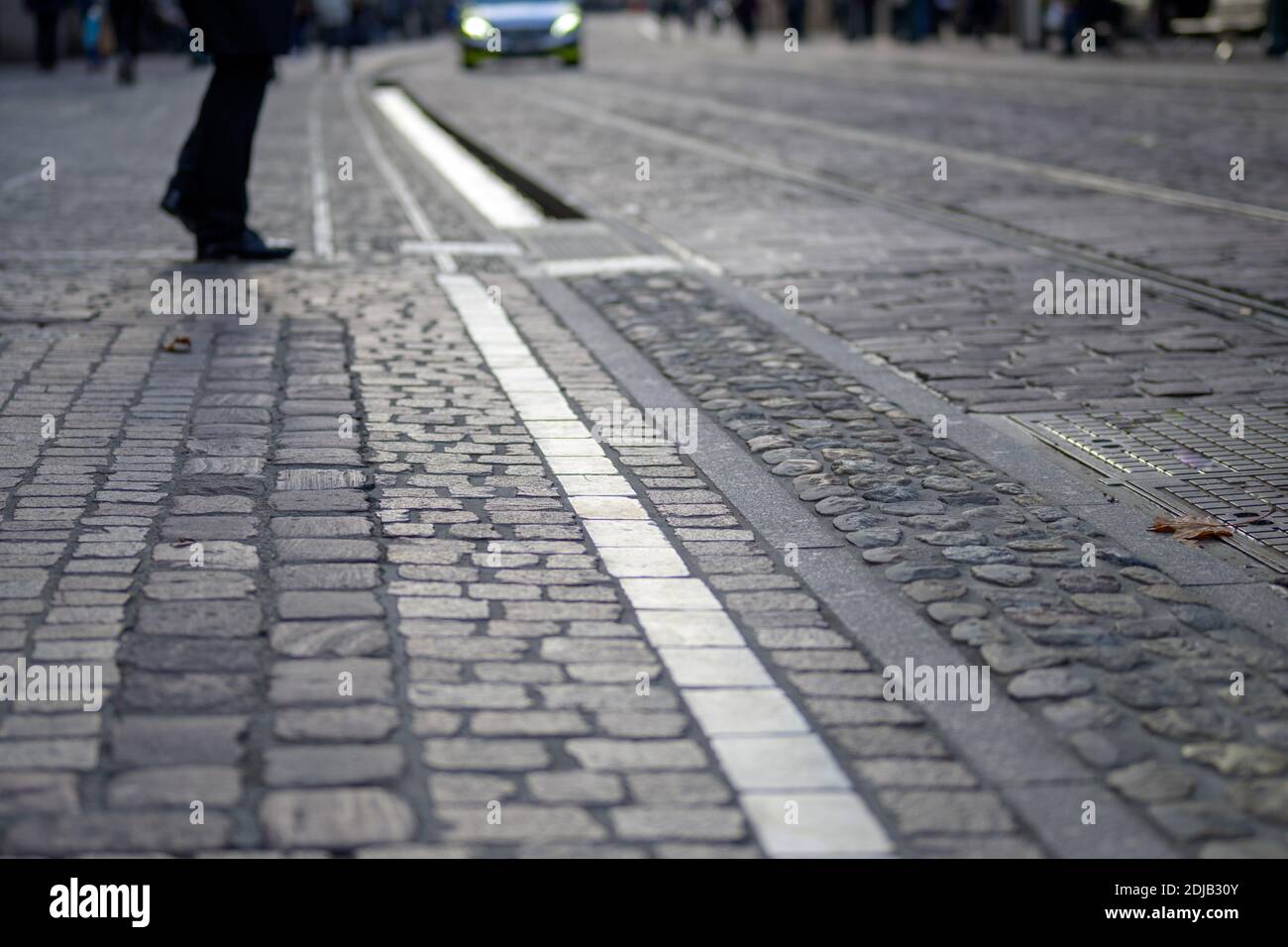 Pavimentazione della strada di Friburgo, Germania. La strada della città lastricata con le pietre di diverse dimensioni, colore e forma, e con la famosa Bächle Foto Stock