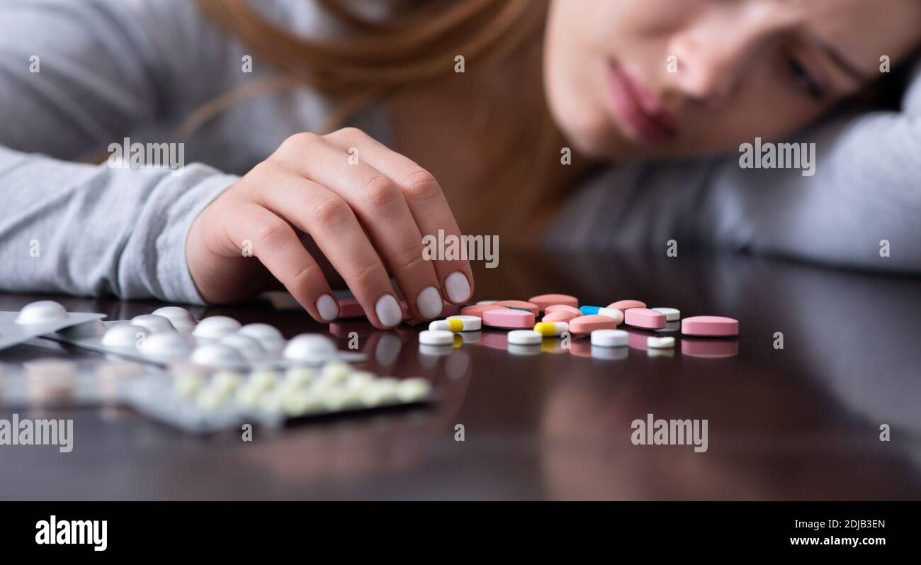 Esaurimento emotivo e suicidio. Closeup di giovane donna depressa con pillole che pianificano di uccidersi, banner design Foto Stock