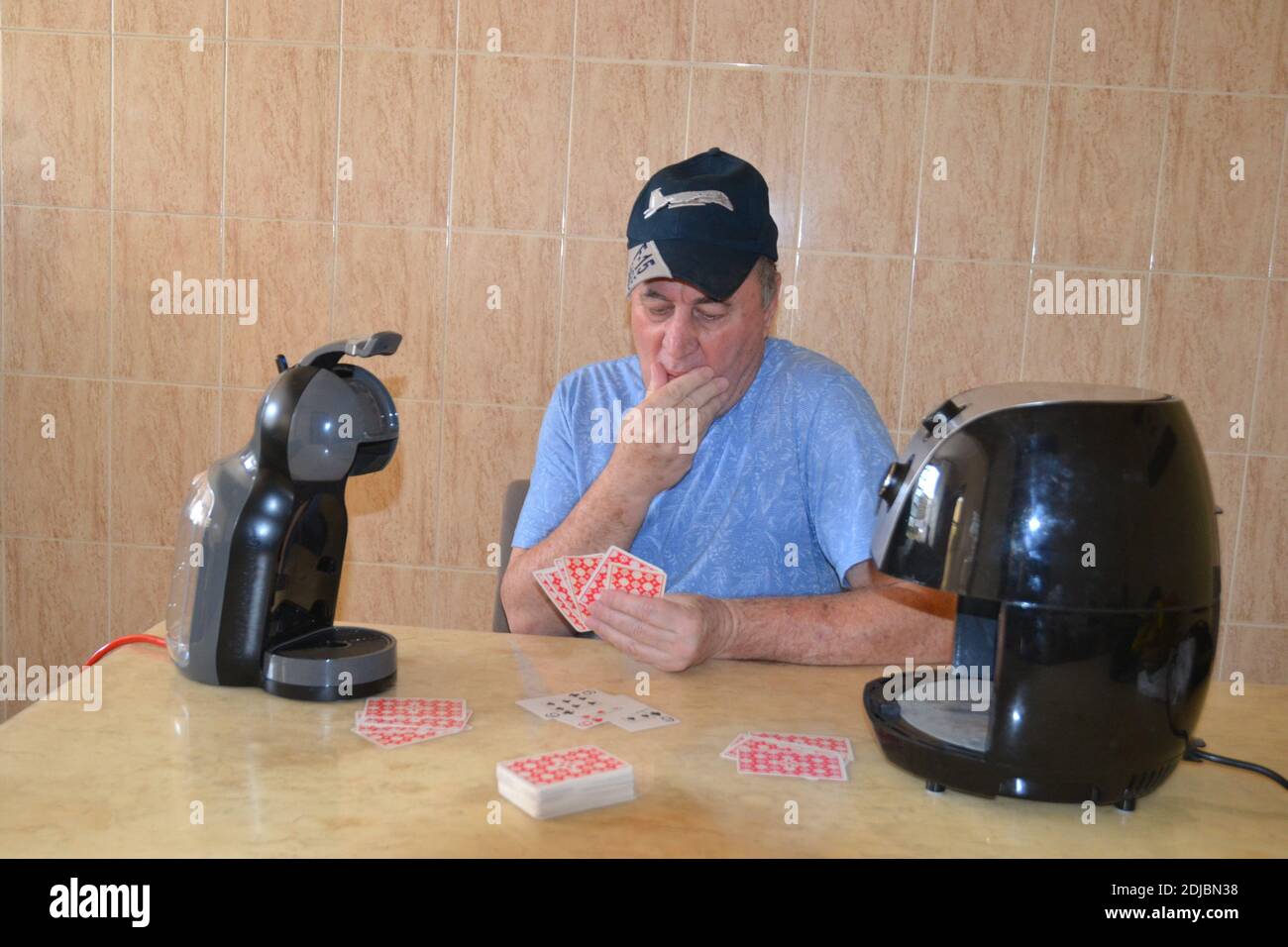 L'uomo anziano gioca a carte con i suoi nuovi amici Il Covid 19 quarantena dopo 9 mesi a casa Foto Stock