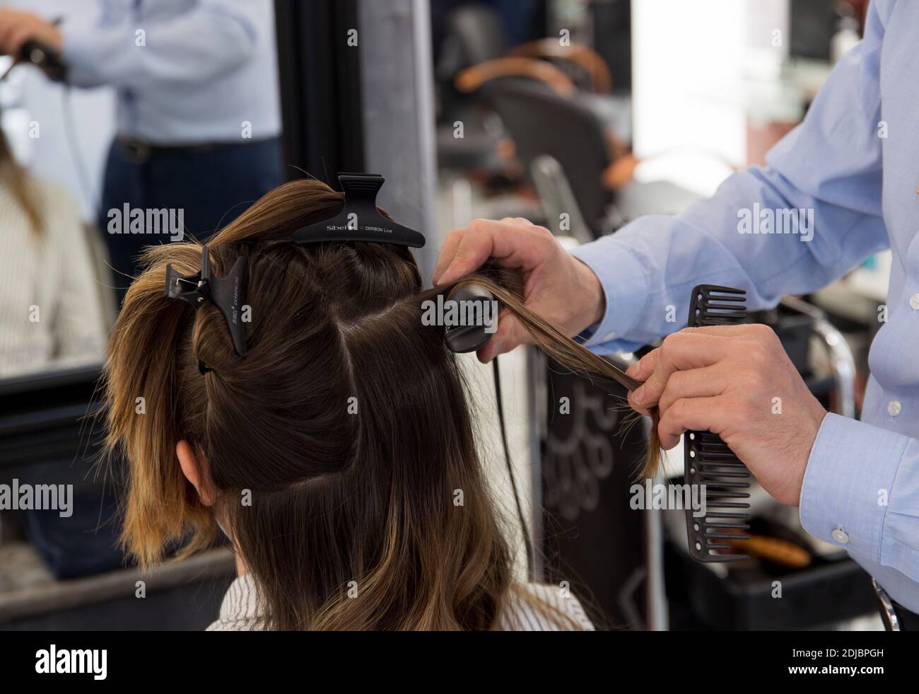 Donna, cliente, che ha i suoi capelli tagliati in un parrucchiere. Capelli di media lunghezza con piastra per capelli Foto Stock