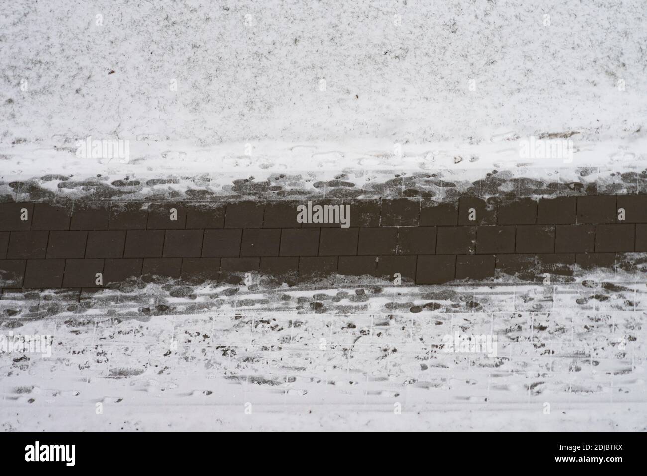 Manutenzione di strade e marciapiedi in inverno. Marciapiede pulito nevoso e impronte umane sul sentiero pedonale. Vista aerea Foto Stock