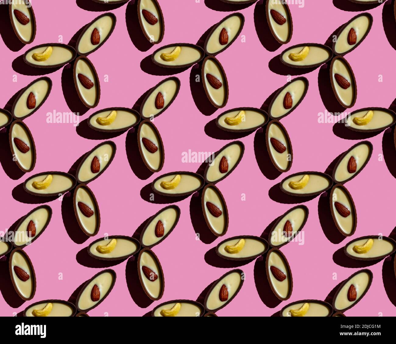 Motivo senza cuciture di caramelle al cioccolato con noci su sfondo rosa. Foto Stock