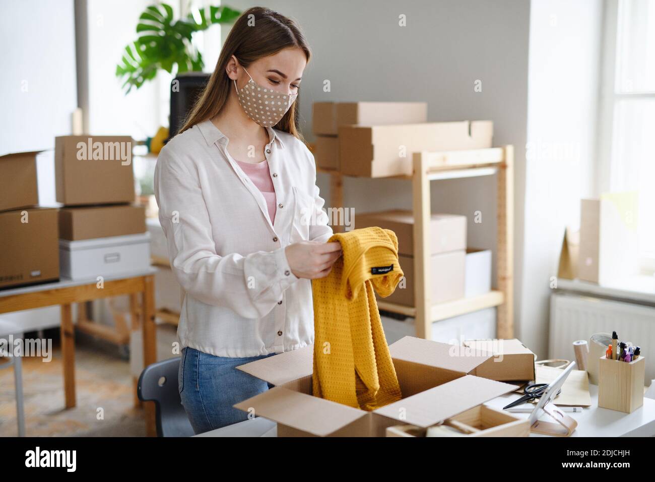 Giovane donna dropshipper che lavora a casa, elaborando gli ordini. Concetto di coronavirus. Foto Stock