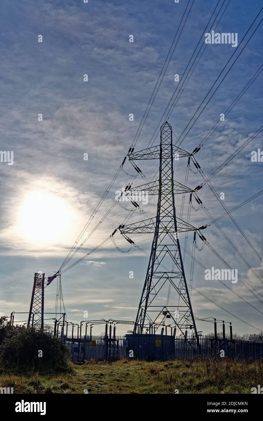 Nazionale griglia pilone contro un cielo blu e un sole flaring, Byfleet Surrey Inghilterra UK Foto Stock