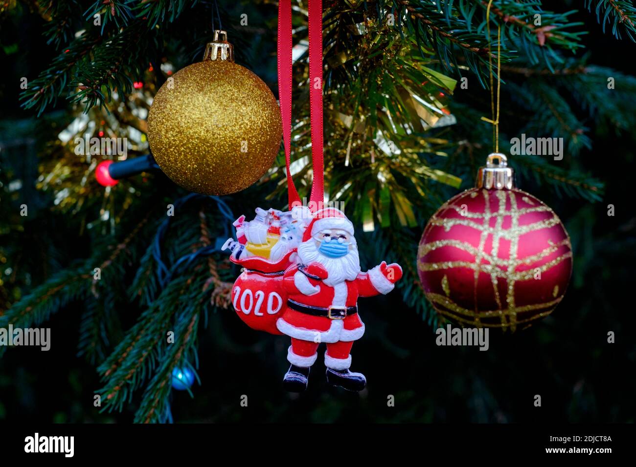 babbo natale indossando maschera decorazione appesa sull'albero di natale durante la pandemia del coronavirus 2020 Foto Stock
