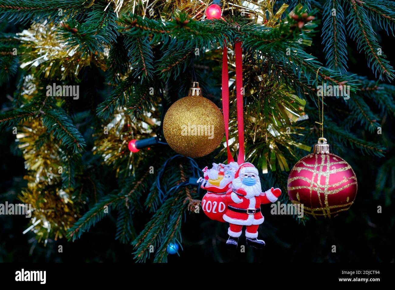 babbo natale indossando maschera decorazione appesa sull'albero di natale durante la pandemia del coronavirus 2020 Foto Stock