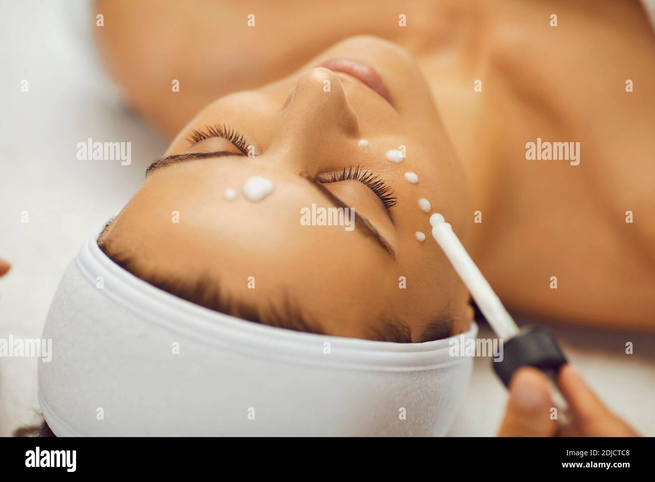 Primo piano di donna con gli occhi chiusi ottenere la procedura di ringiovanimento facciale con siero idratante. Foto Stock