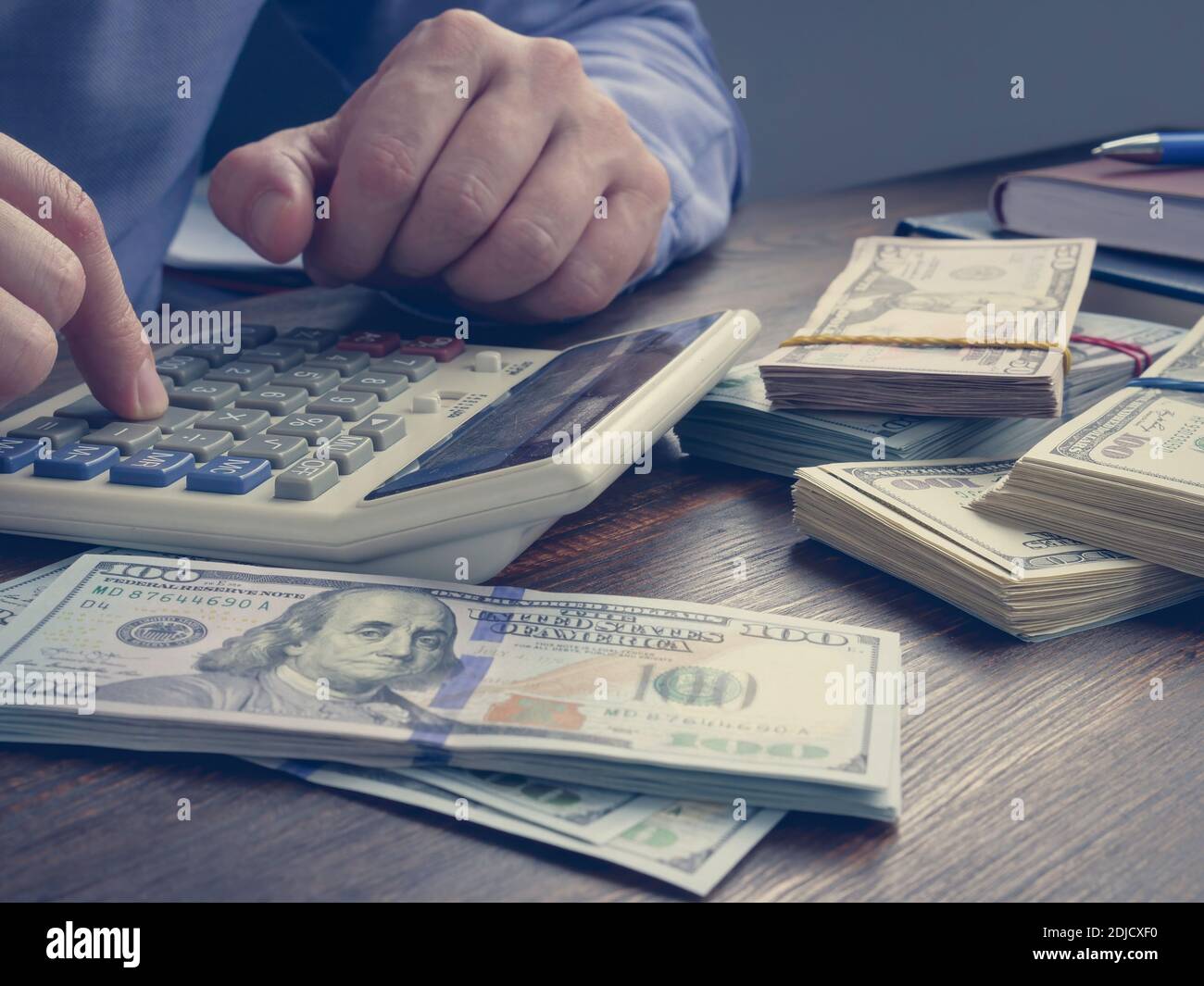 L'uomo conta i soldi su una calcolatrice. Primo piano di mani e una pila di contanti. Foto Stock