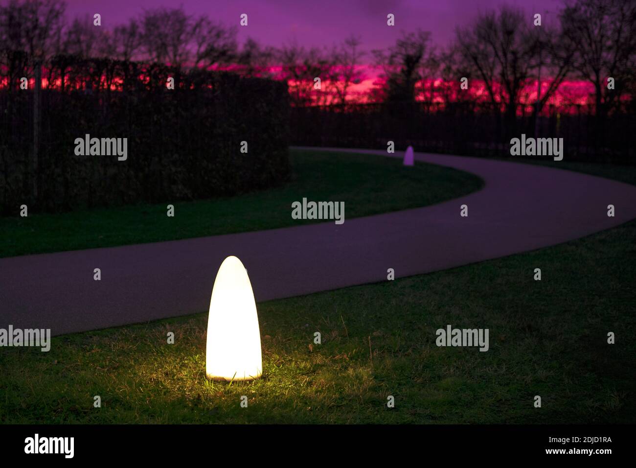 Luci notturne nel parco. Vicolo nel parco pubblico con cielo tramonto. Lanterna bagna nel giardino notturno. Percorso vuoto. Atmosfera. Foto Stock