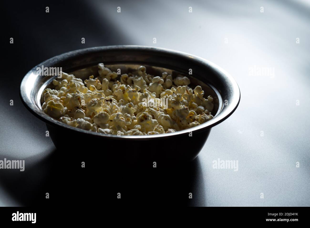 Secchio di popcorn preparato su una parte anteriore del grande monitor, su uno sfondo nero. Foto Stock