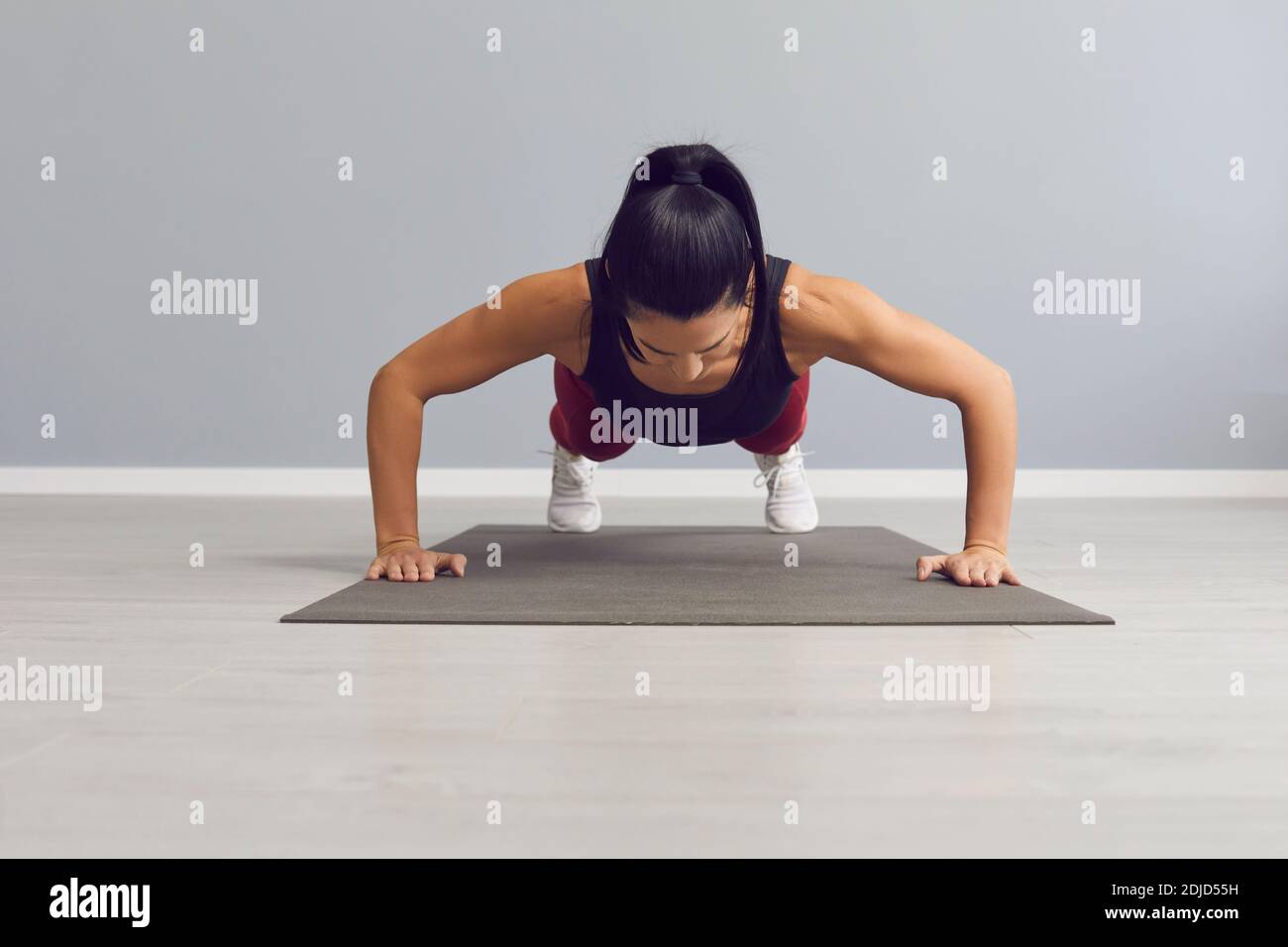 La donna atletica fa i push-up per riscaldare i muscoli pettorali, i triceps e le spalle. Foto Stock