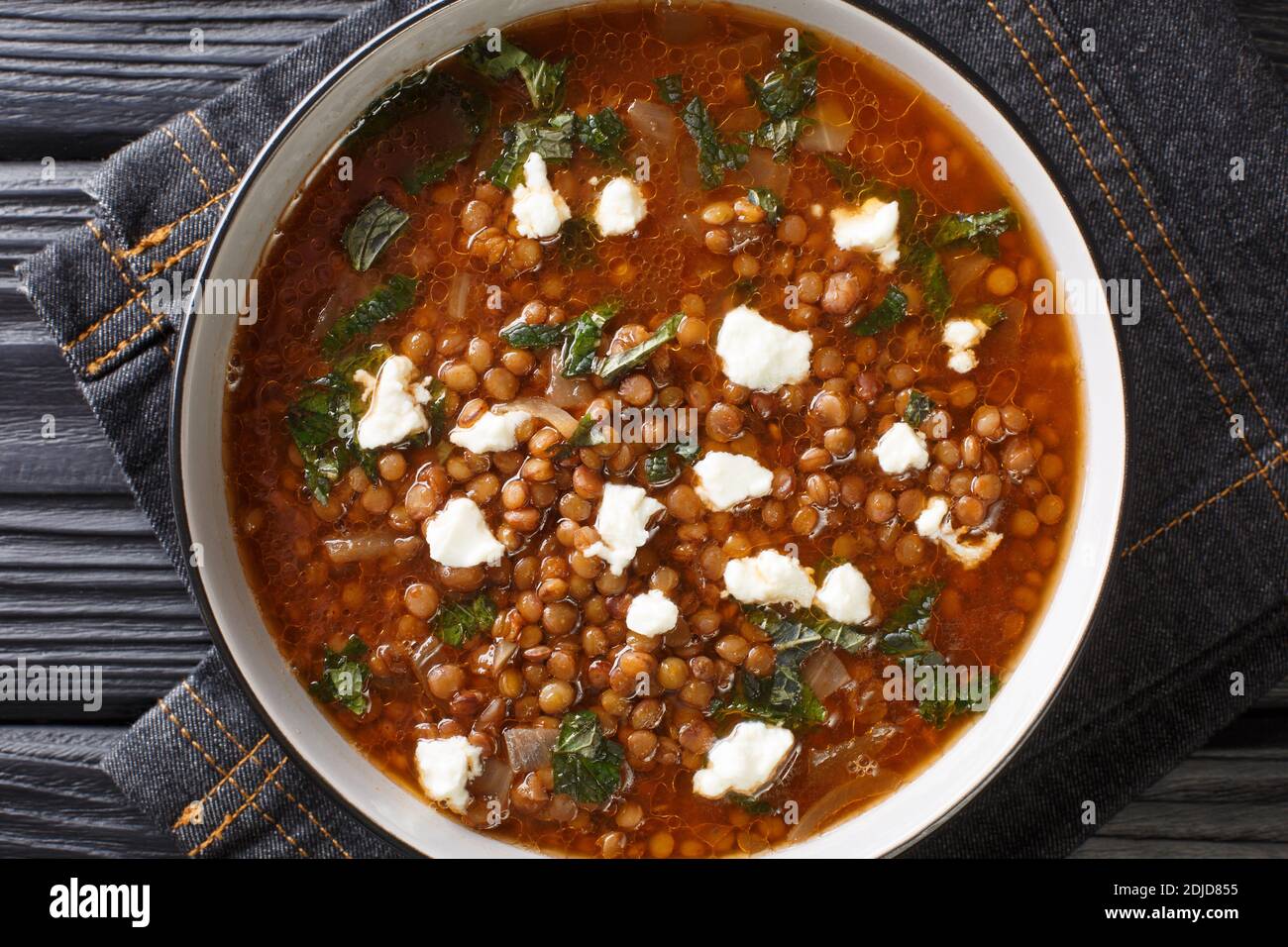 Deliziosa zuppa con lenticchie marroni e feta in primo piano in un piatto sul tavolo. Vista dall'alto orizzontale Foto Stock