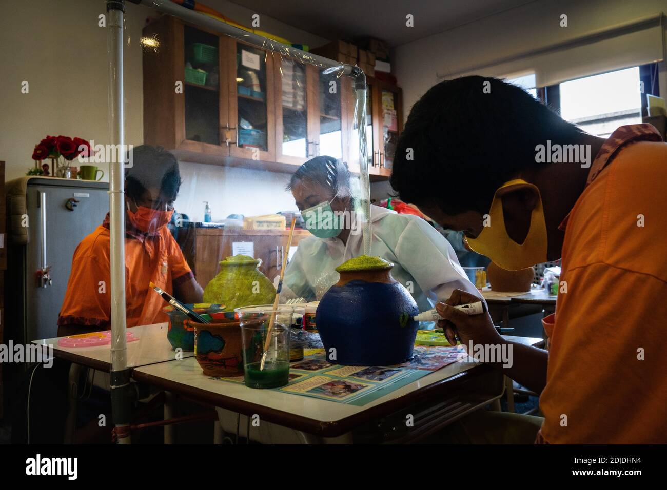 BALI/INDONESIA-OTT 23 2020: I bambini con disabilità fisiche imparano a colorare. Sono accompagnati da un terapeuta. Usano maschere e hamzat Foto Stock