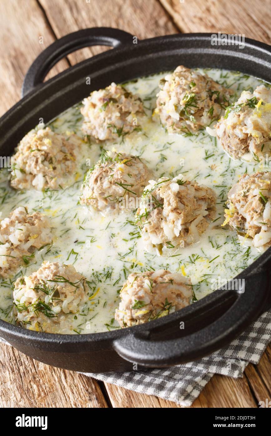 Polpette greche con riso in salsa di yogurt con primo piano di limone in un piatto sul tavolo. Verticale Foto Stock