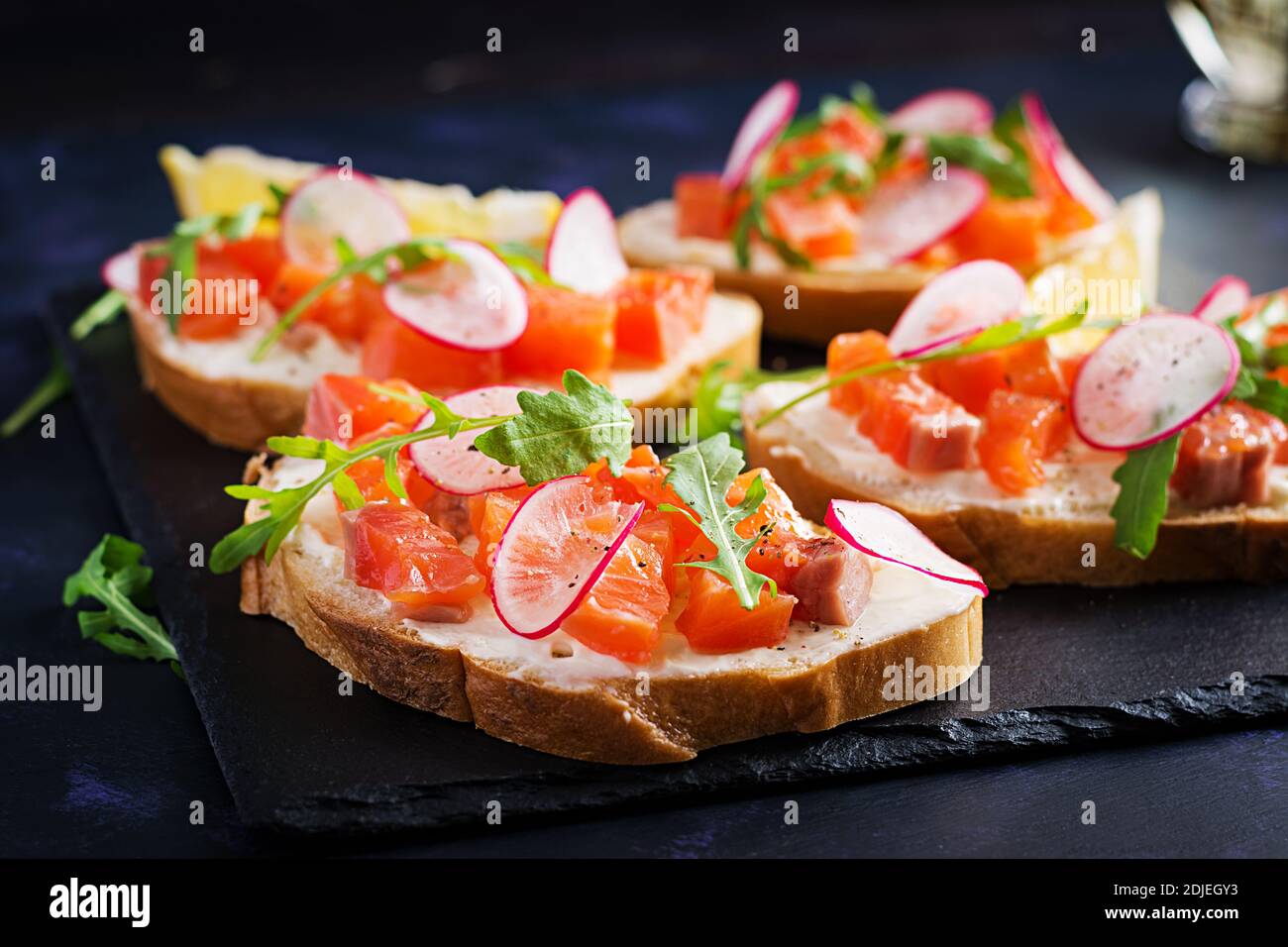 Sandwich con salmone salato per una sana colazione su sfondo scuro. Menu pesce. Foto Stock