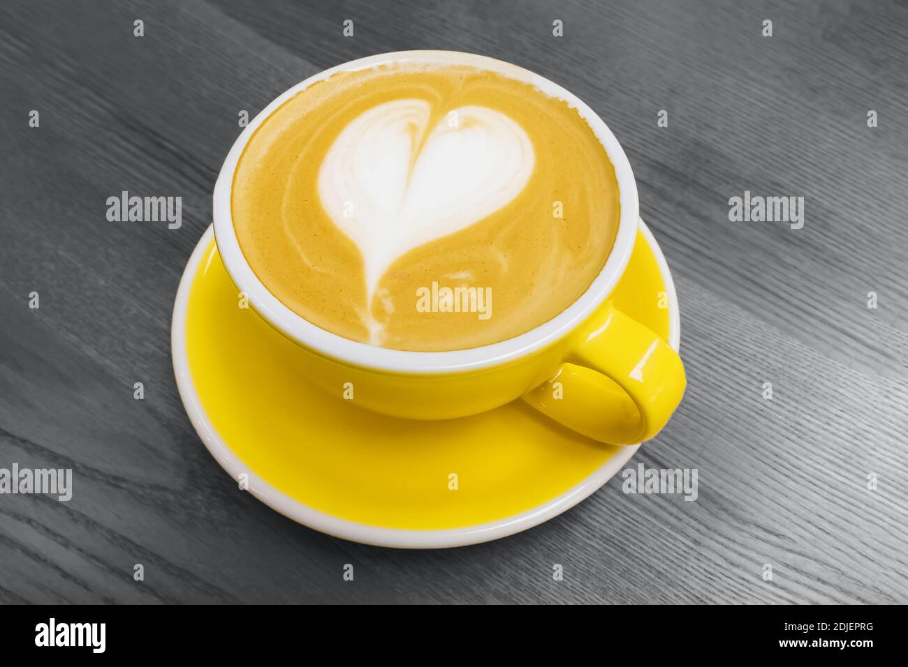 Tazza di caffè giallo con latte art a forma di cuore Foto Stock