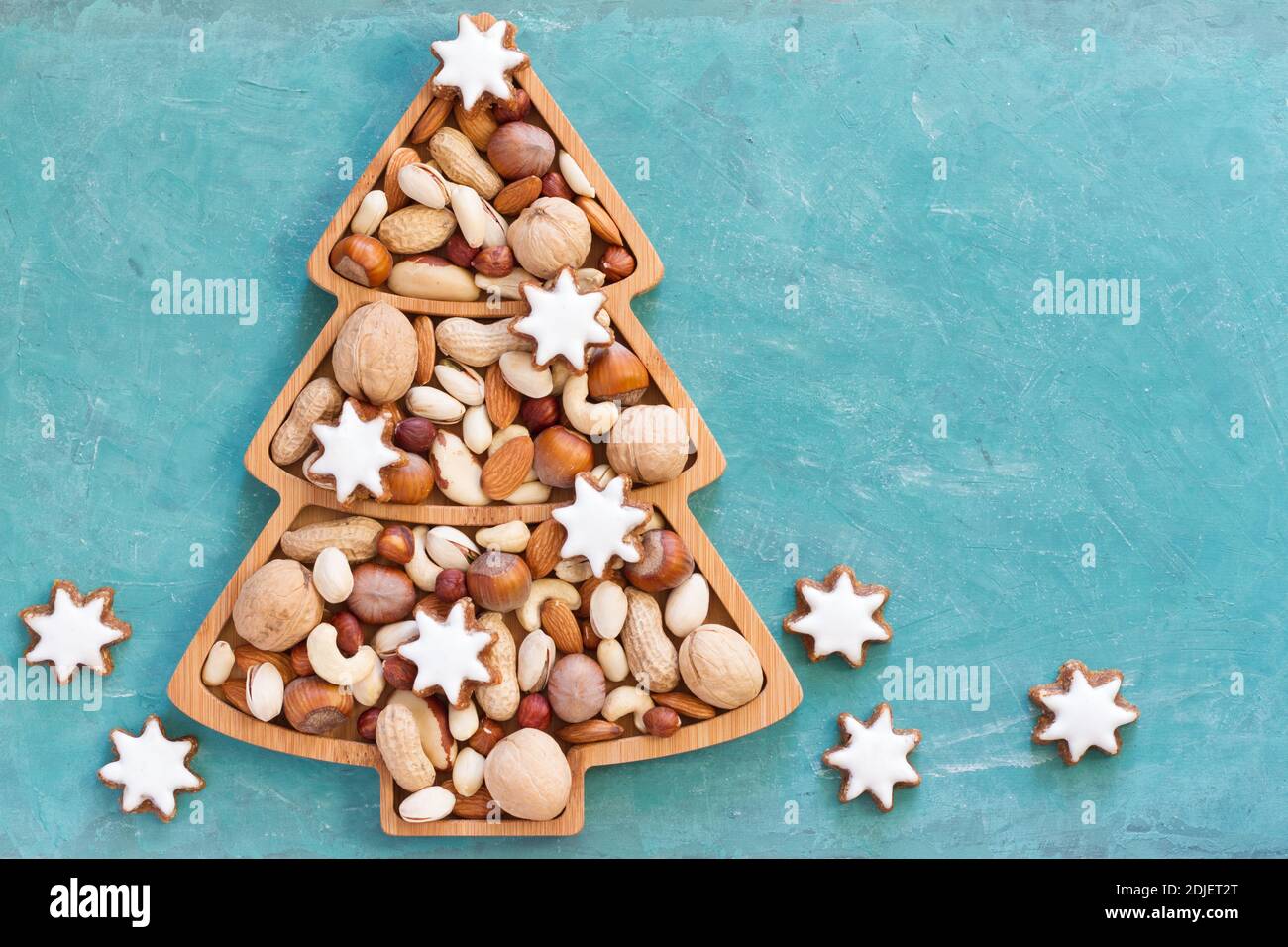 Noci e biscotti in ciotola a forma di albero di Natale su sfondo blu Foto Stock