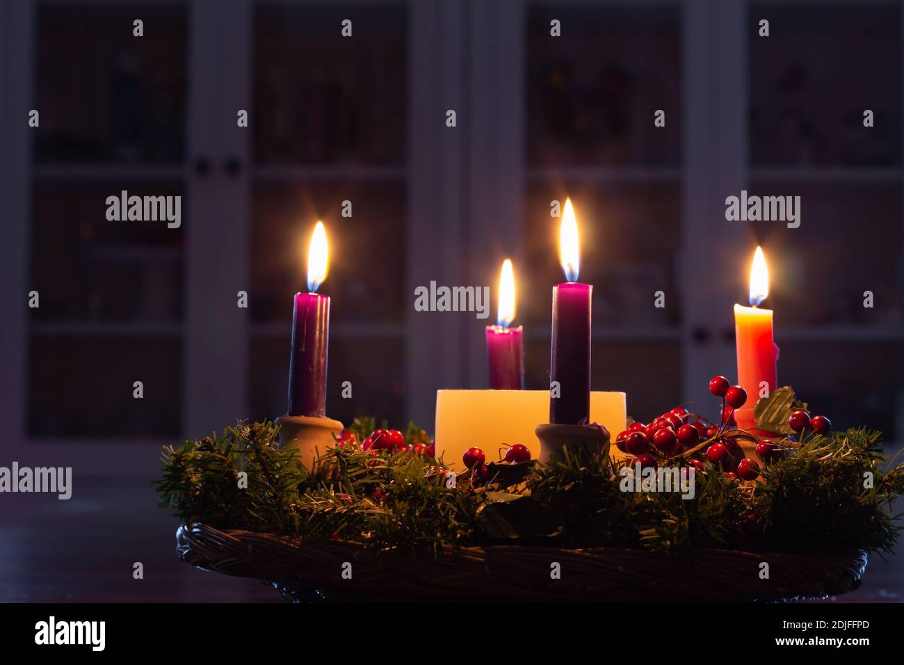 Corona dell'Avvento di Natale con candele che bruciano luminose in camera buia Foto Stock