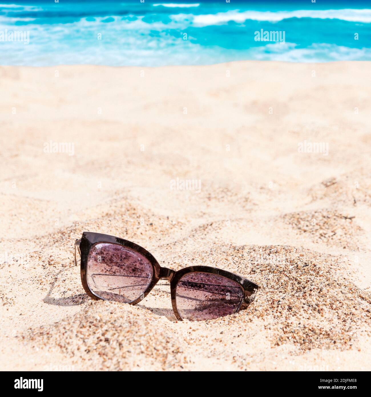 Vecchio perso abbandonato gli occhiali da sole sulla spiaggia di sabbia con il turchese mare Caraibi in background in una luminosa giornata estiva. L'estate tropicale Concetto di vacanza Foto Stock