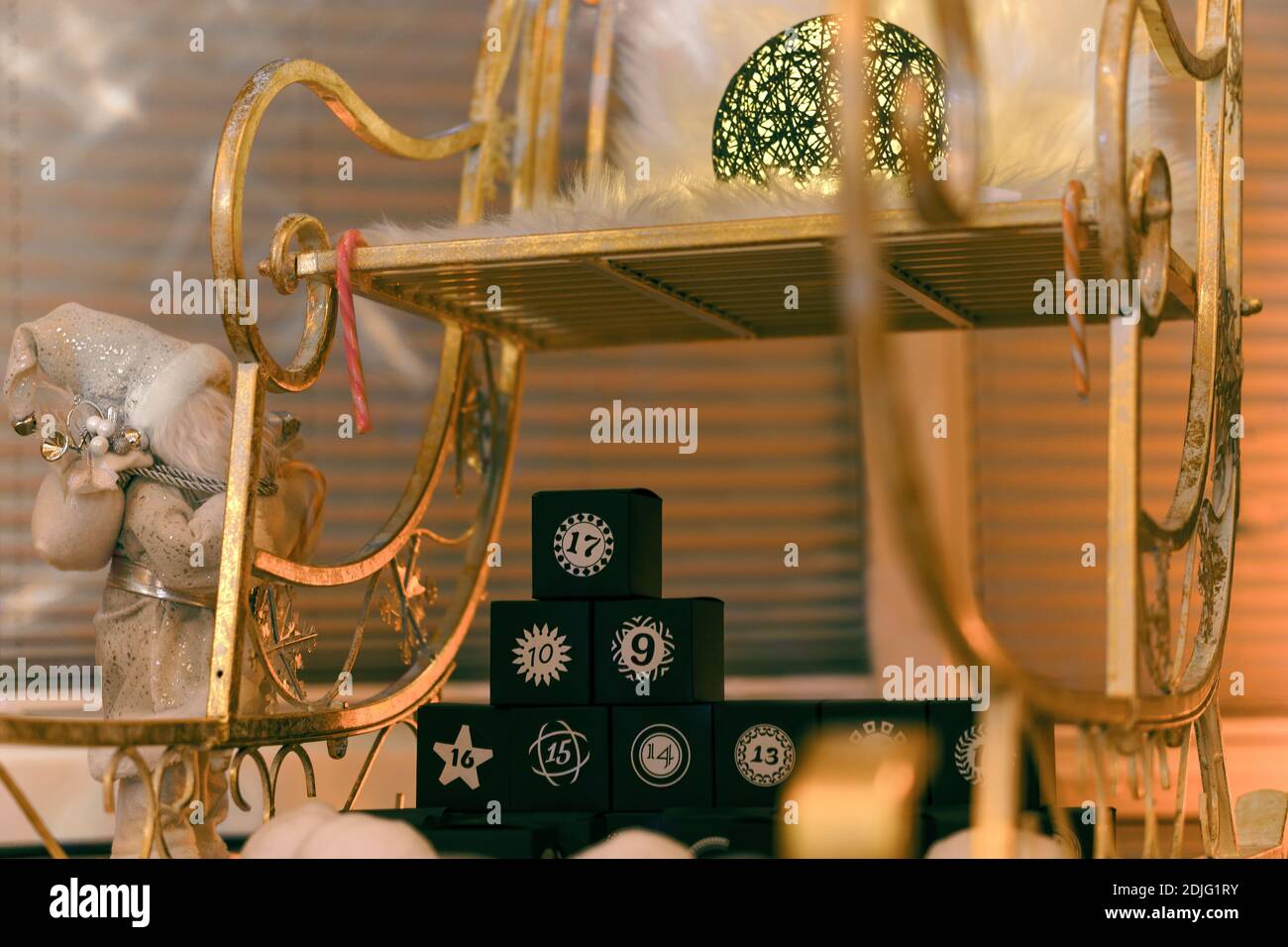 Una slitta dorata di Natale in un ambiente festivo con un calendario in cubi neri numerati Foto Stock