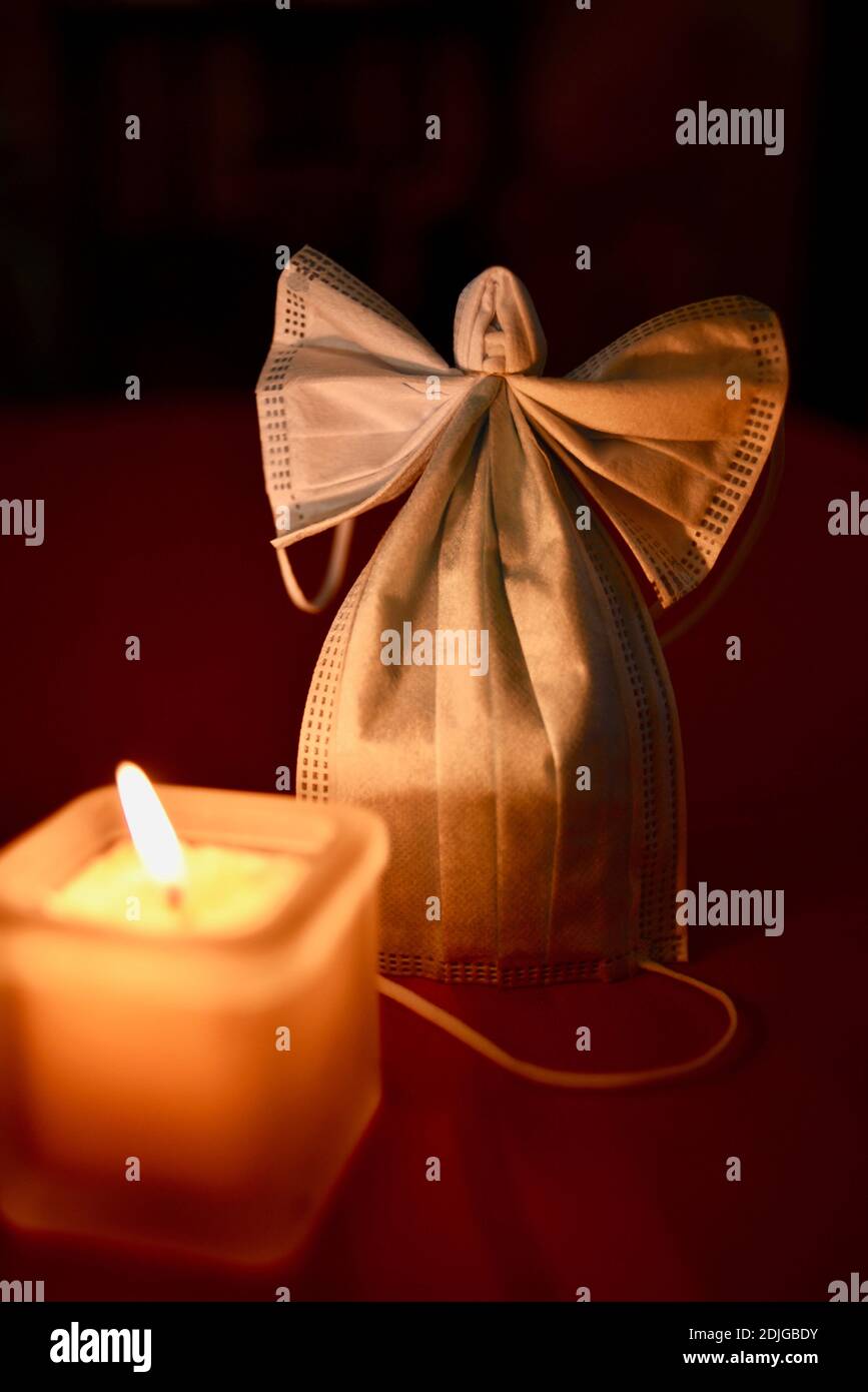 Due maschere chirurgiche si sono formate nella forma pazzolante di un angelo con le ali, candela incandescente, offrendo speranza in covid-19 pandemia di sofferenza negli Stati Uniti. Foto Stock