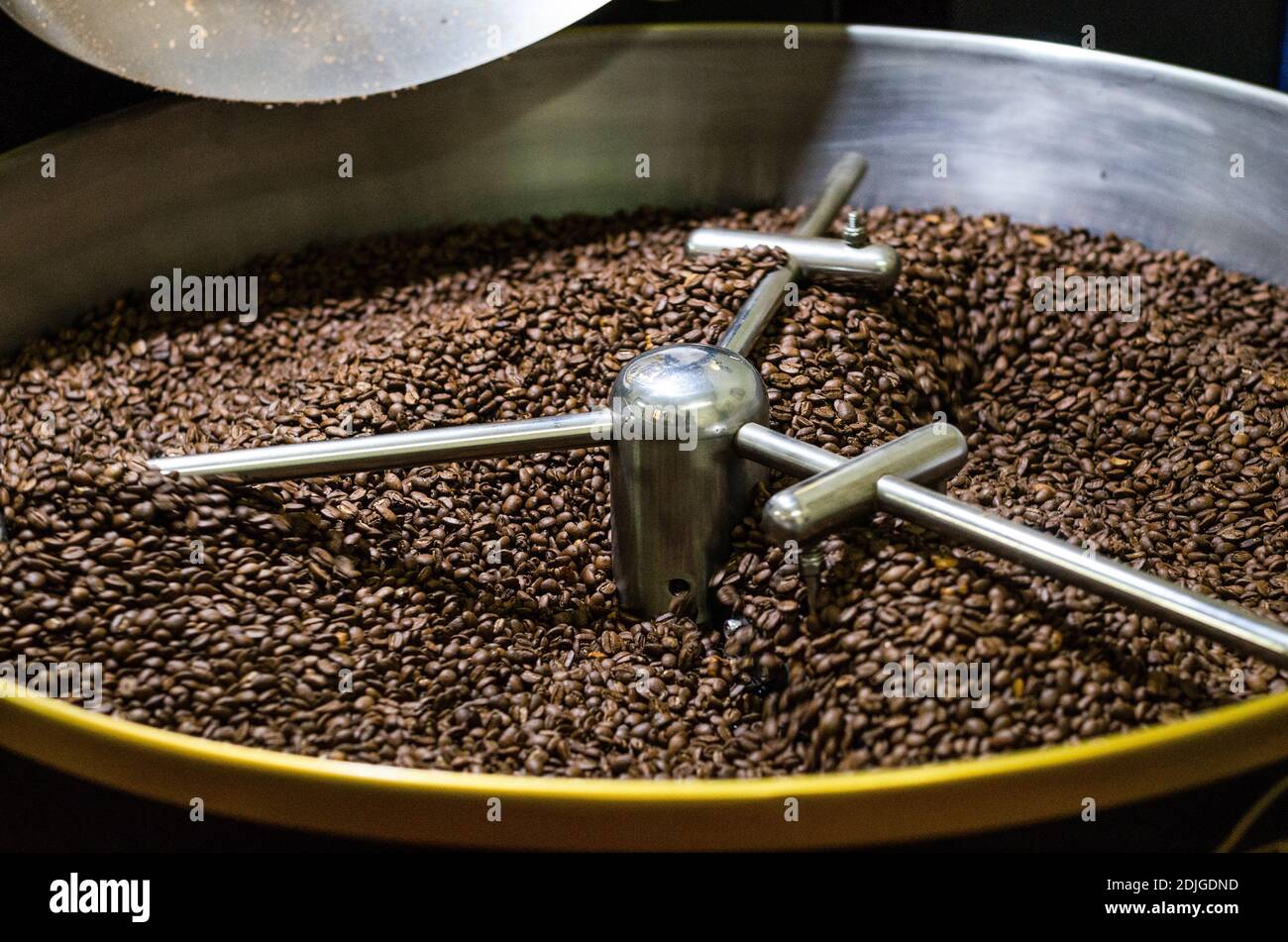 Chicchi di caffè appena tostati da un'ampia e moderna tostatura di caffè vengono agitate nel cilindro di raffreddamento Foto Stock