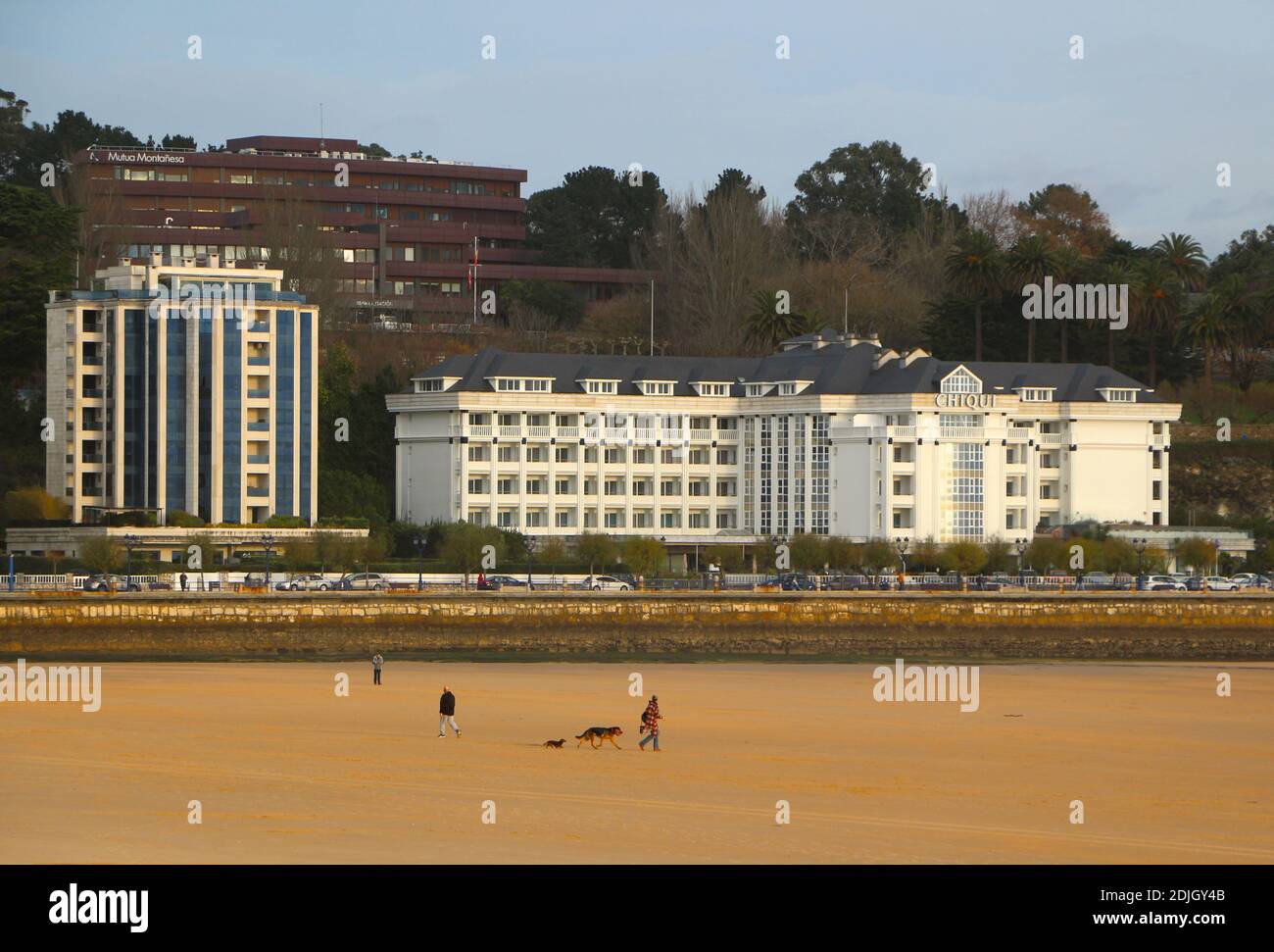 Gente cane a piedi sulla spiaggia su un ventoso fresco tardo autunno mattina Sardinero Santander Cantabria Spagna Hotel Chiqui Appartamento edificio Foto Stock