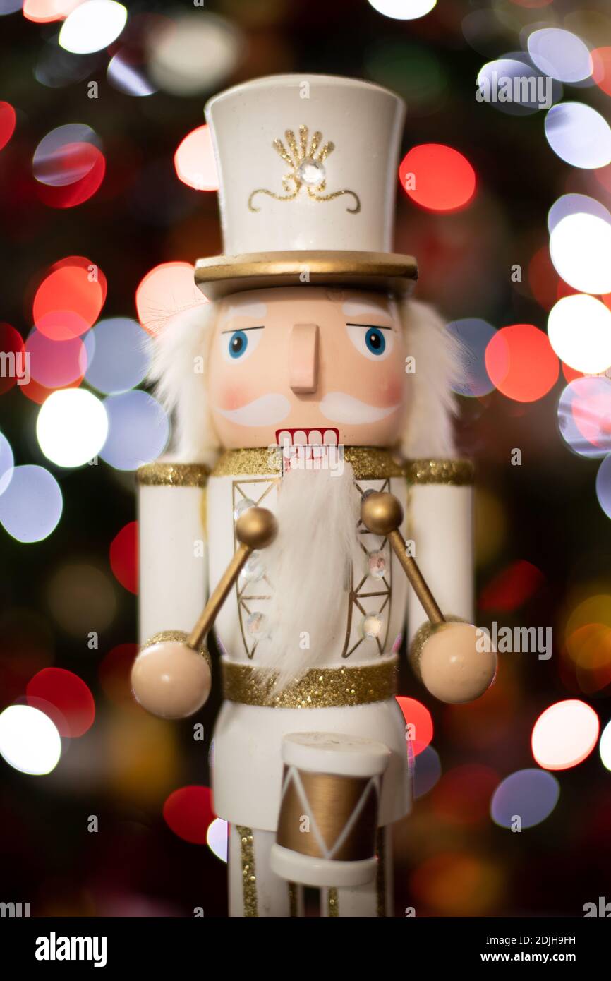 Statuetta frontale classico soldato batterista nutcracker con bianco e oro Uniforme e tamburo davanti all'albero di Natale sfocato Foto Stock