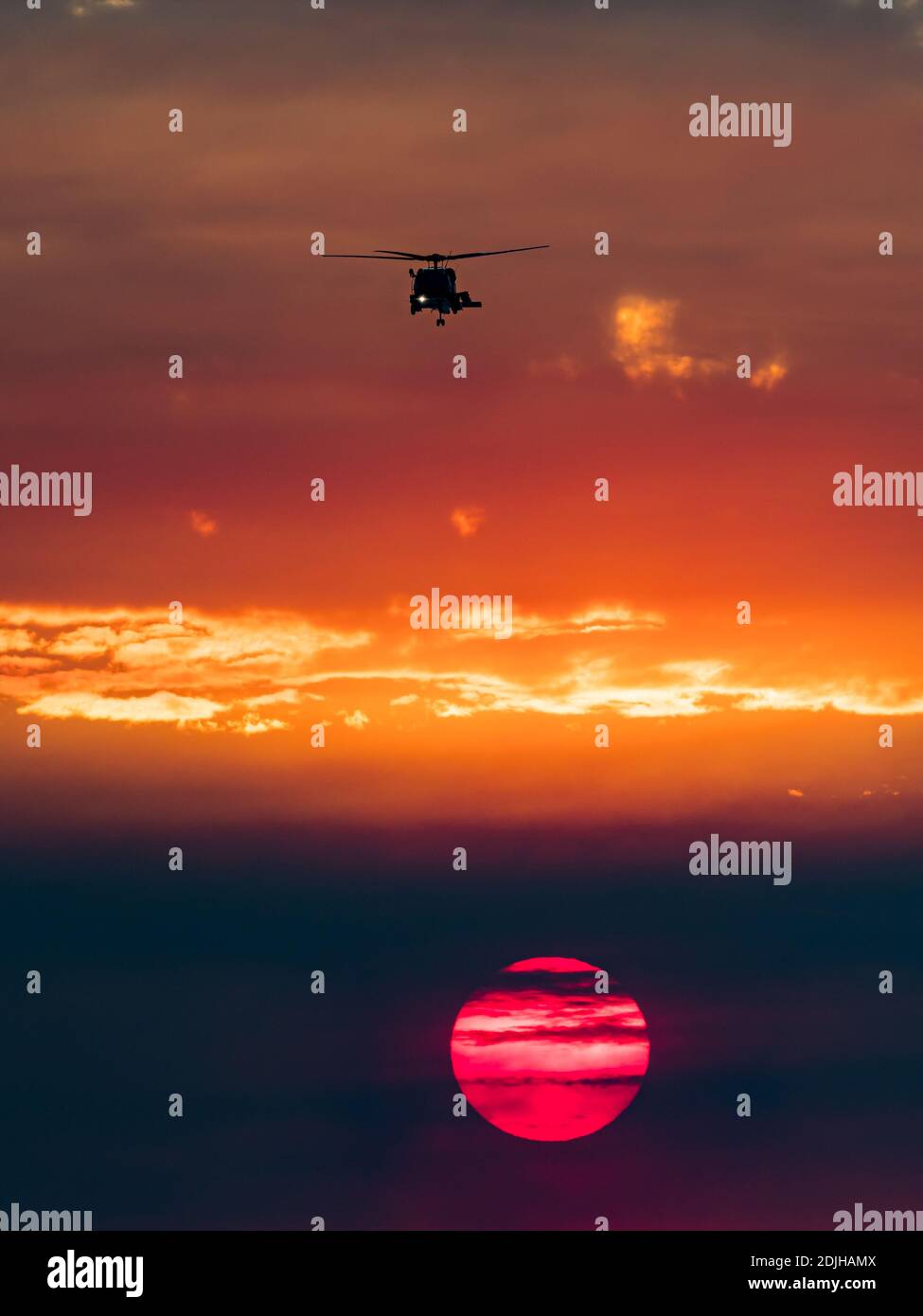 Elicottero militare e il sole che tramonta sul surf a la Jolla Shores, California, con fumo da un fuoco durante i venti di Santa Ana Foto Stock