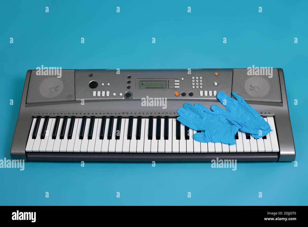 vista dall'alto dei guanti medici blu sulle chiavi del sintetizzatore elettronico, simbolo di protezione contro virus e batteri, isolati su sfondo blu Foto Stock