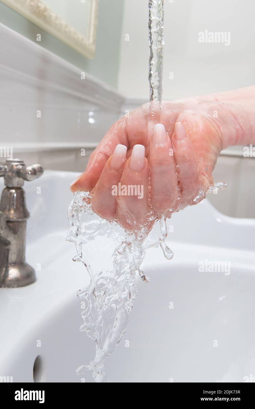 Donna lavando le mani sotto acqua corrente Foto Stock