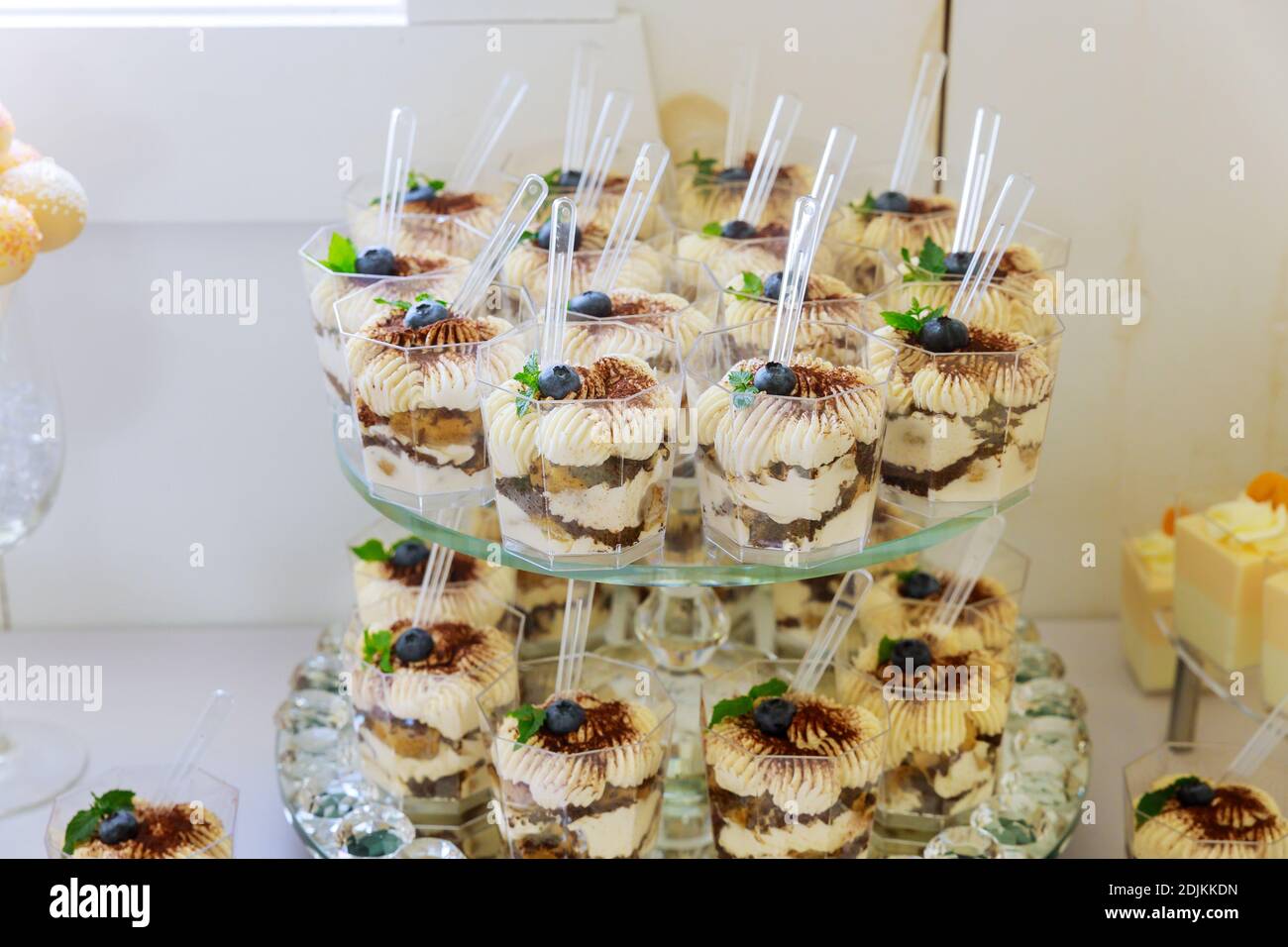 Budino, torta di libbra e bacche in tazze sul supporto della torta. Mini dessert trifle. Foto Stock