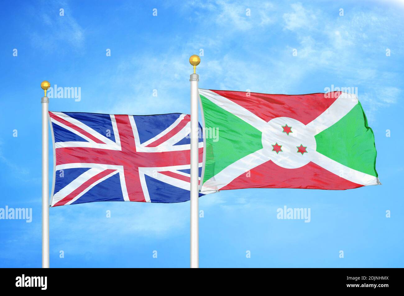 Regno Unito e Burundi due bandiere su flagpoli e blu cielo nuvoloso Foto Stock