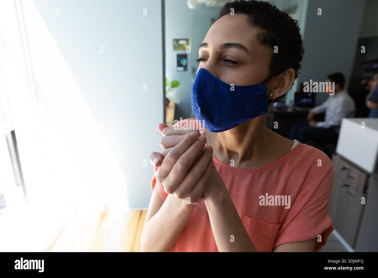 Razza mista donna che indossa maschera viso sanitizzando le mani Foto Stock