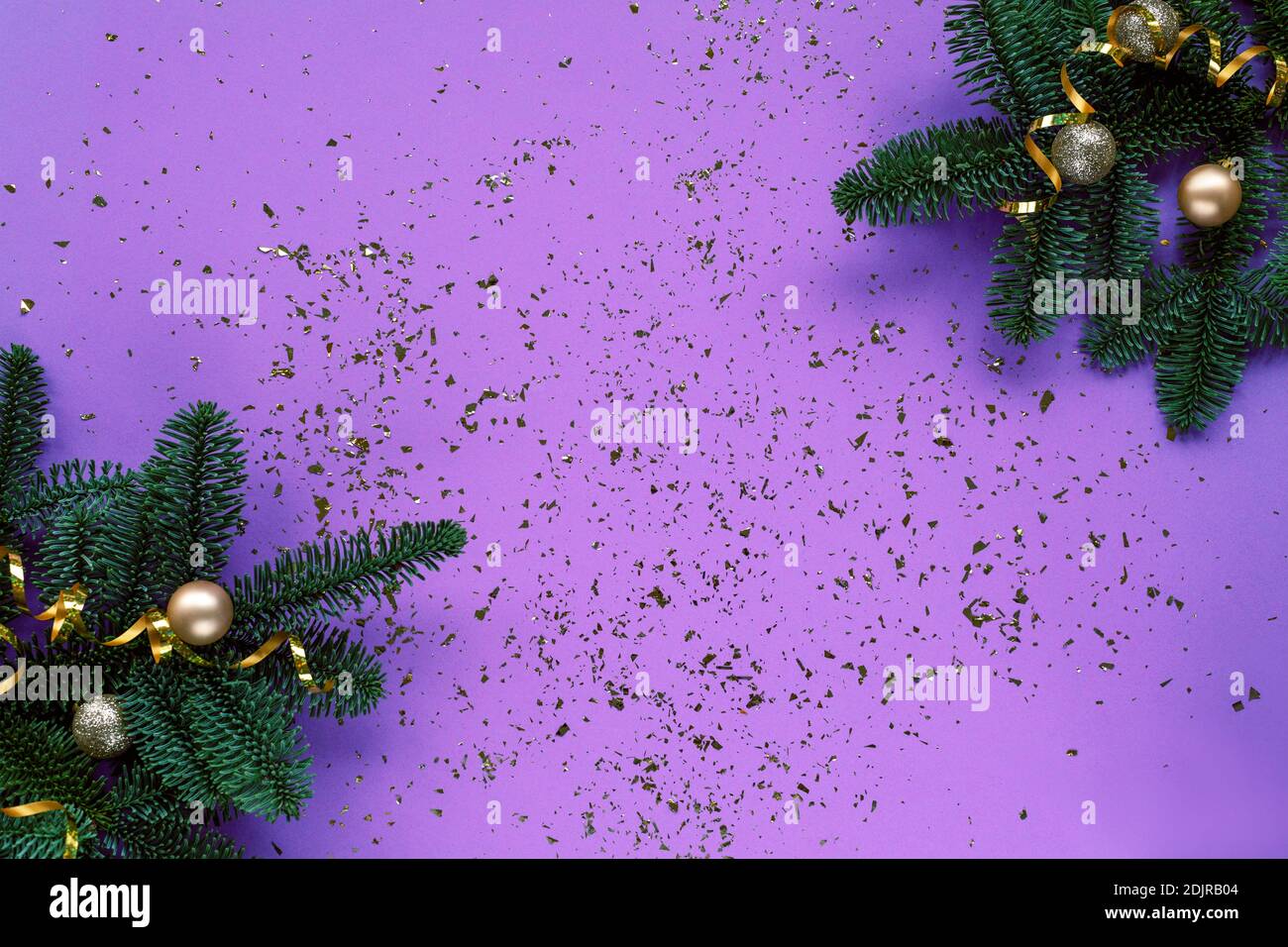 Rami di abete, baubles su sfondo viola con confetti. Concetto di Natale. Vista dall'alto, disposizione piatta, spazio per la copia Foto Stock