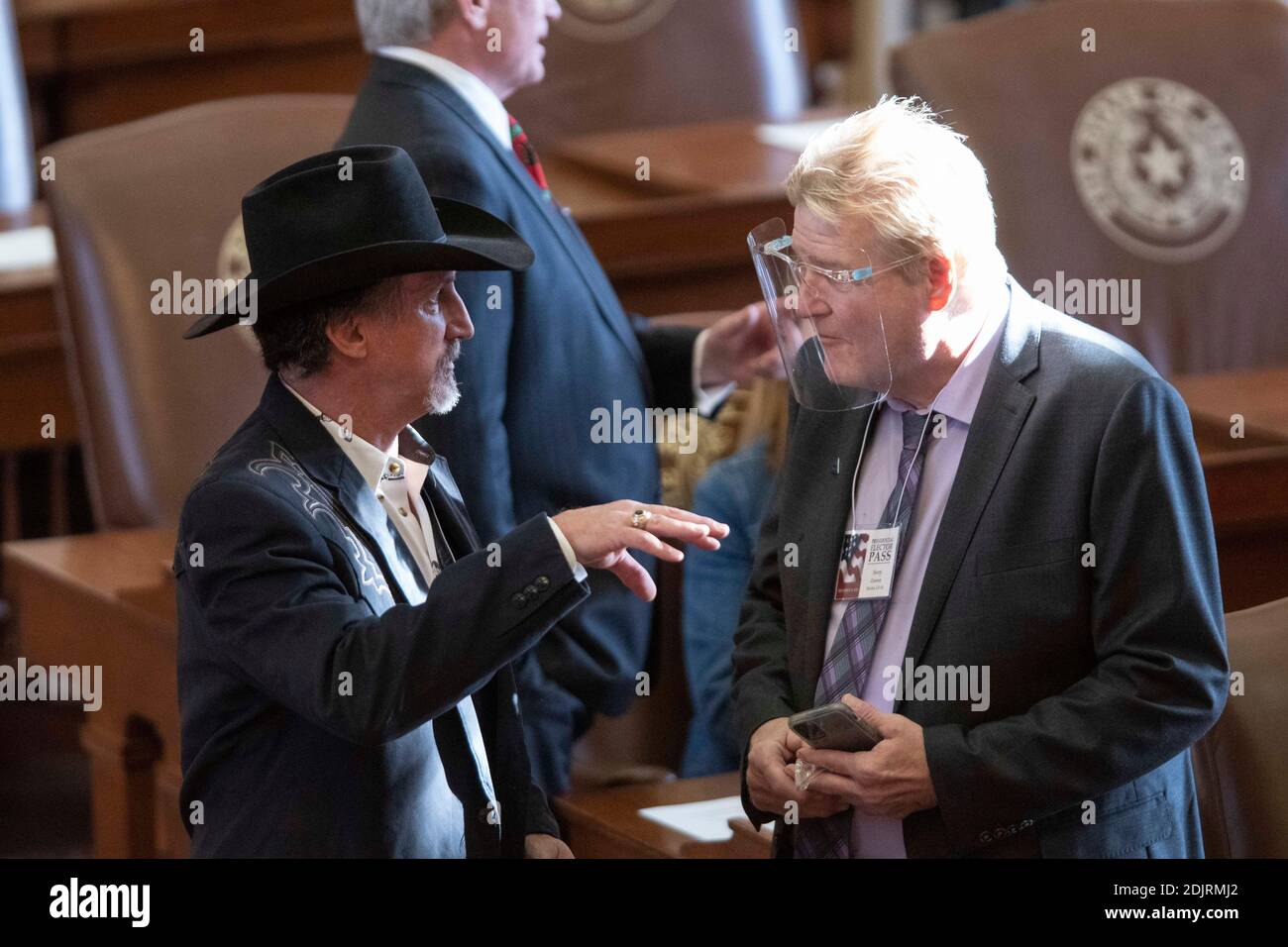 Austin, Texas, Stati Uniti. 14 dicembre 2020. L'elettore Richard Hall (l) non indossa alcuna maschera mentre parla con l'elettore Harry Zenner, che indossa uno schermo facciale secondo i protocolli COVID-19. Gli elettori presidenziali del Texas hanno lanciato i voti per il presidente Donald Trump al collegio elettorale lunedì pomeriggio in Camera. Come previsto, tutti i 38 voti del Texas sono andati al presidente e al vicepresidente. Credit: Bob Daemmrich/Alamy Live News Foto Stock