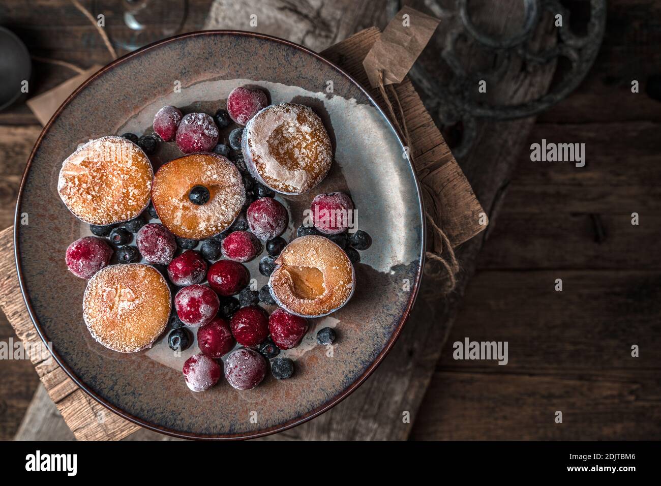 Piatto con frutti di bosco surgelati e panna su fondo di legno. Foto Stock